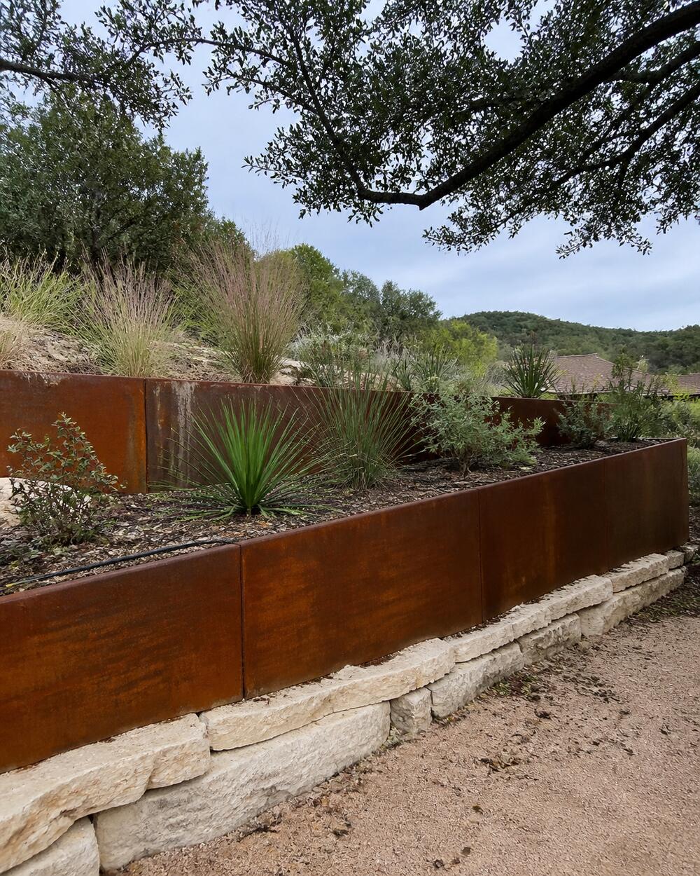 Terraced Corten steel planters pinned to limestone on a sloped Austin, TX lot