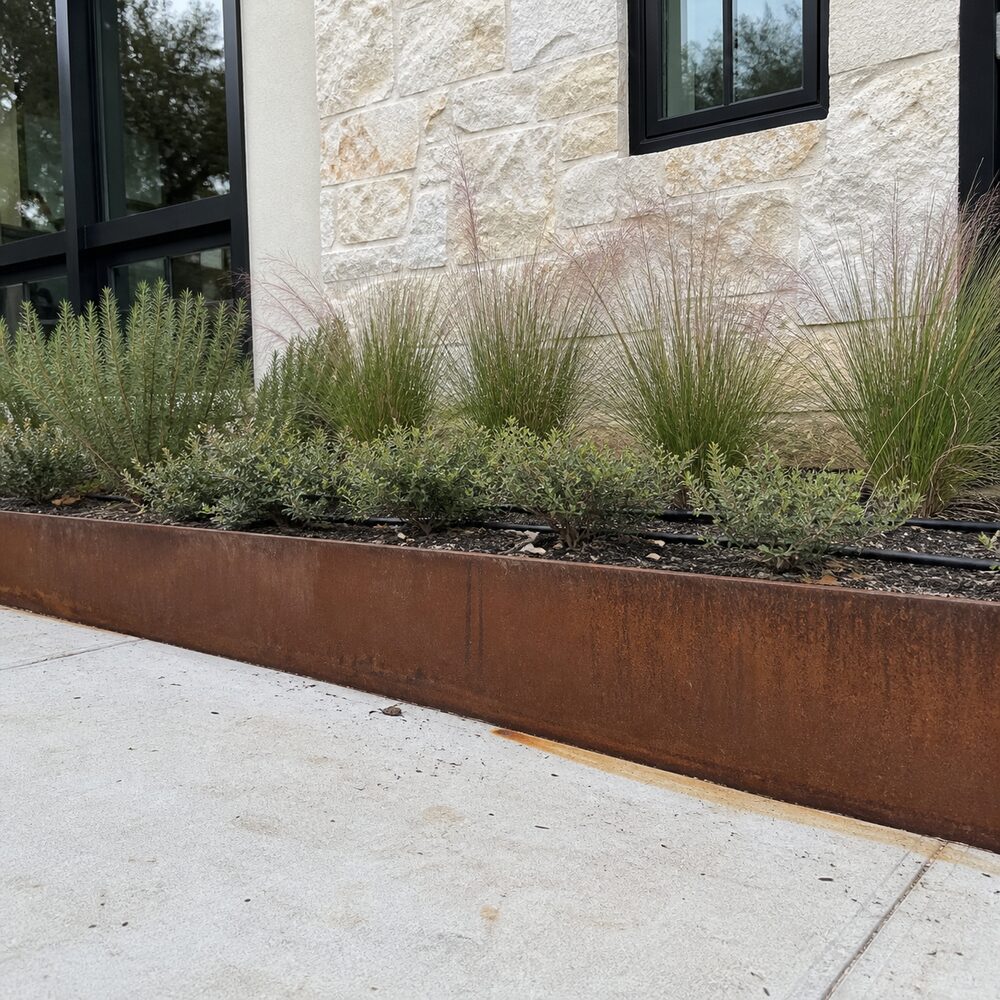 Low Corten steel planter running along a limestone house wall in Austin, TX